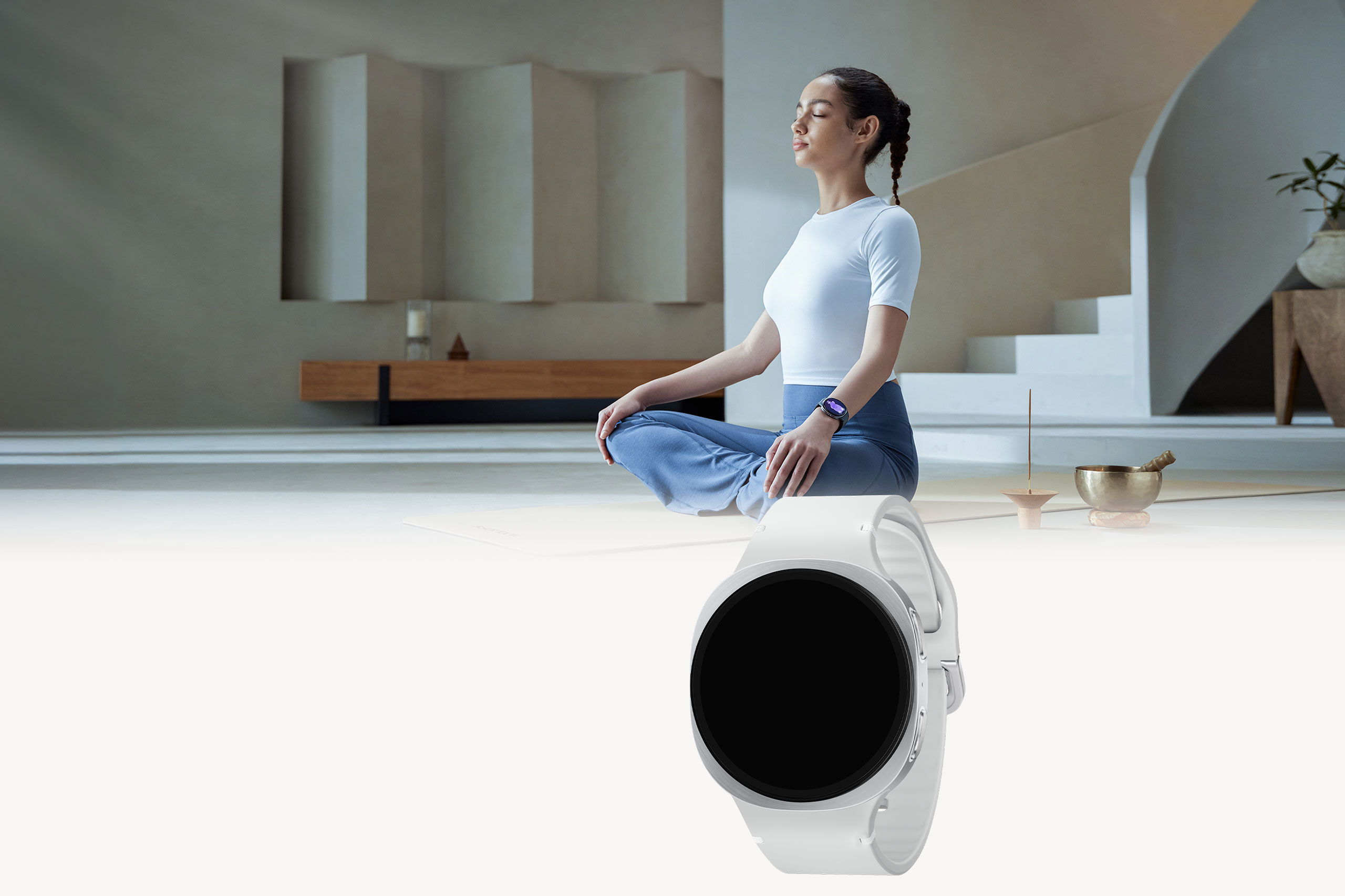 A woman sitting cross-legged indoors with her eyes closed, wearing Galaxy Watch8 on her wrist.